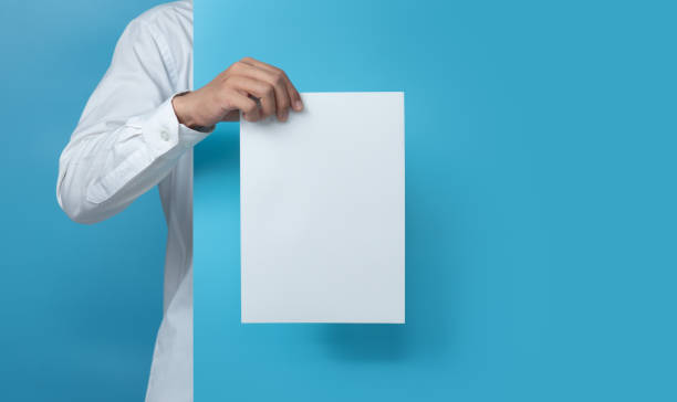 istock Young man holding blank paper on blue background,copy space for text 1294521753