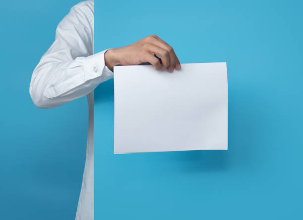 istock Young man holding blank paper on blue background,copy space for text 1294522383