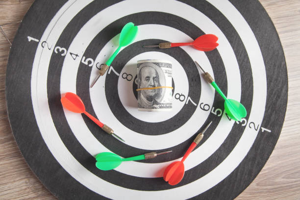 istock Dart arrows and money on target dartboard. 1294540939