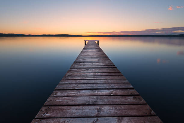 old wooden pier at sunset. long exposure, linear perspective - reflection imagens e fotografias de stock