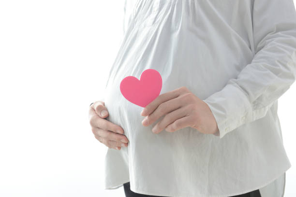 istock Pregnant woman with heart object on white background 1294544803