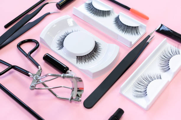 istock Different tools for eye lash extension on trendy pastel pink background. Creative knolling concept. Fake eyelashes, tweezers, brush and eyelash curler. Beauty pattern. Makeup cosmetics. 1294545432
