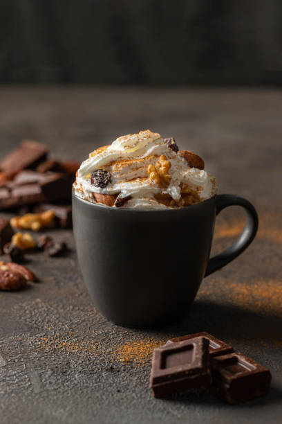 istock Hot chocolate cocoa cup with whipped cream decorated with cinnamon, chocolate slice and nuts  on concrete background. Traditional beverage for cold days concept. 1294545651