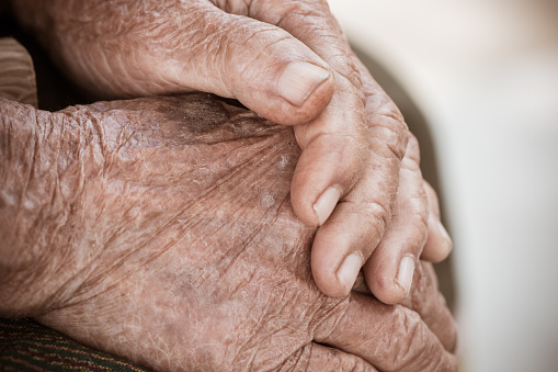 Hands Asian elderly woman grasps her hand on lap, pair of elderly wrinkled hands and Traces of hard work, World Kindness older and Adult care  concept. Senior citizen is a common euphemism for an old person