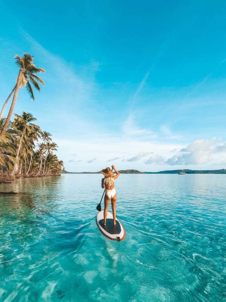 frau genießt stand up paddle boarding in den tropen - beach tourist resort one person one woman only stock-fotos und bilder
