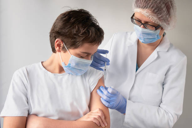 close-up on hands in gloves with syringe and shoulder of the patient, teen kid. covid 19, flu, tetanus or measles vaccine concept. unrecognizable medic, doctor or nurse vaccinates schoolboy - syringe injecting vaccination cold and flu imagens e fotografias de stock
