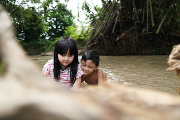 istock Cute Kids Siblings together Playing Sand pebbles at River Rural 1294550156