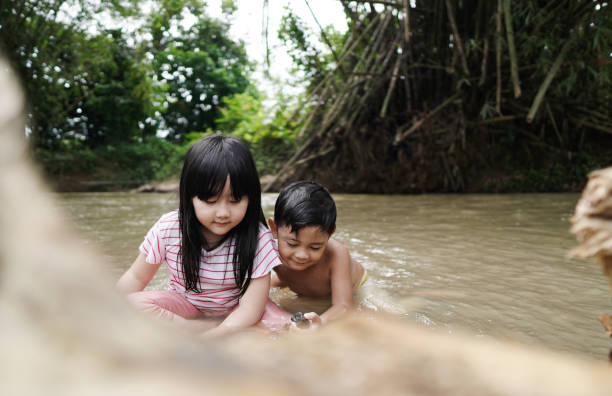 istock Cute Kids Siblings together Playing Sand pebbles at River Rural 1294550175