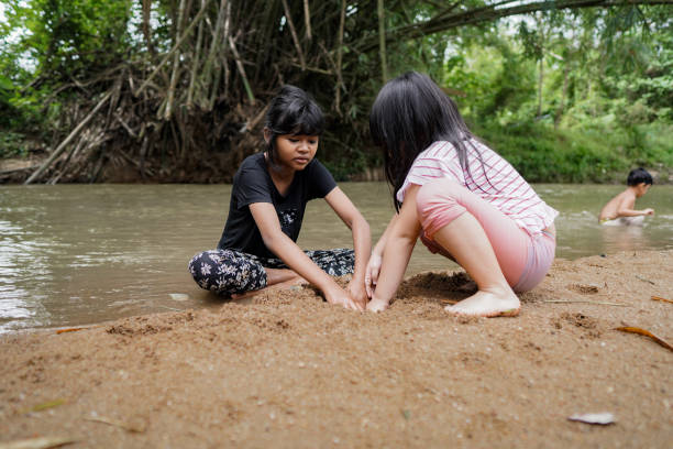 istock Cute Kids Siblings together Playing Sand pebbles at River Rural 1294550202