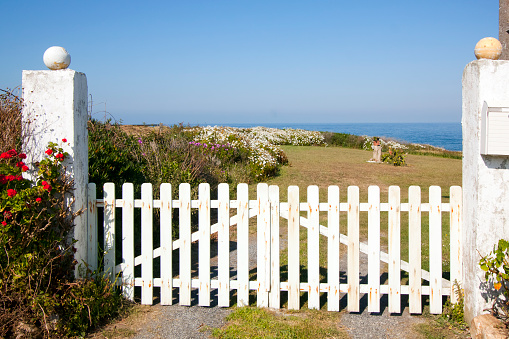 White wooden gate, garden inside, seaview. Foz, A Mariña, Lugo province, Galicia, Spain.