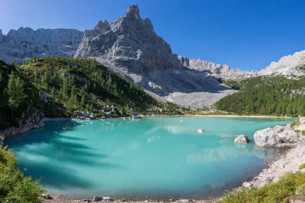 peak of Dito di Dio mountain and green water of lake Sorapis with blue sky