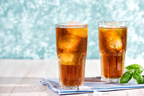 The glass of iced tea on wooden table. Cuba Libre or long island cocktail The glass of iced tea on wooden table. Cuba Libre or long island cocktail, cold drink or lemonade with lemon and basil. Green turquoise on background oolong tea stock pictures, royalty-free photos & images