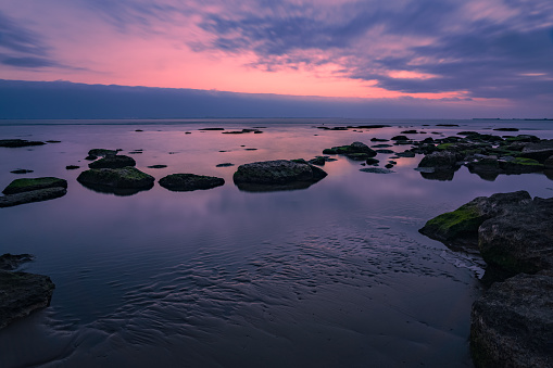 Colorful sunrise on rocky sea coast, long exposure