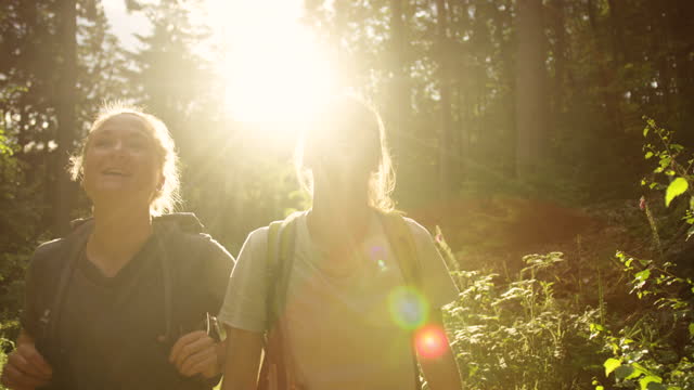 Two women hiking in the mountains with backpacks. Girls on a hike breathing fresh air oxygen. Back to nature