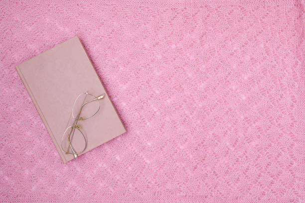 winter flat lay with book and eyeglasses on pink