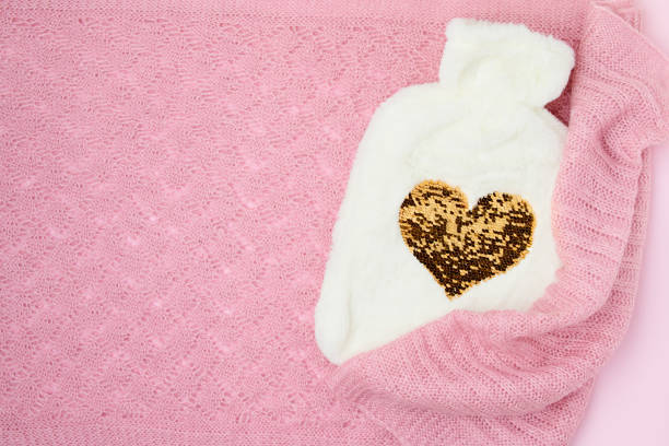 winter flat lay with hot water warmer on pink background.