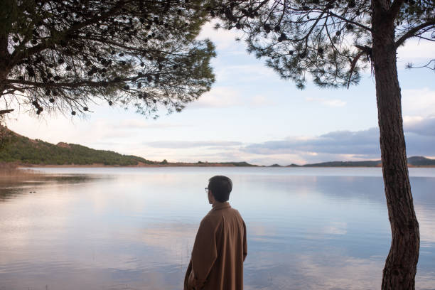 Rear view of a young man by a lake at sunset