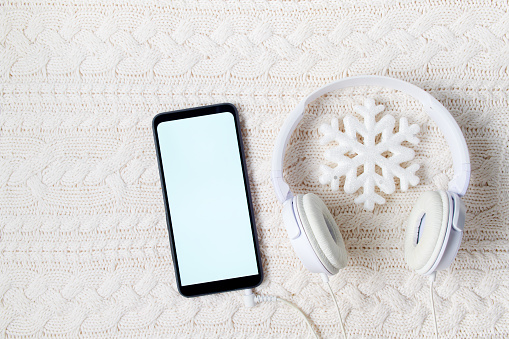 winter flat lay with white headphones and snowflake