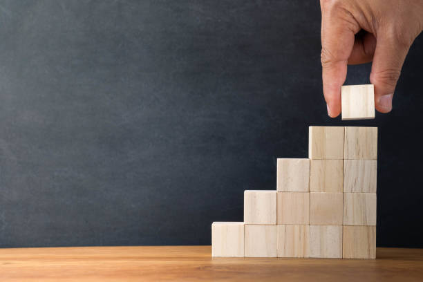 istock Hand arranging wood blocks stacking as step stair on wooden table background. Business investment and finance accounting concept for growth success process with copy space. 1294565901