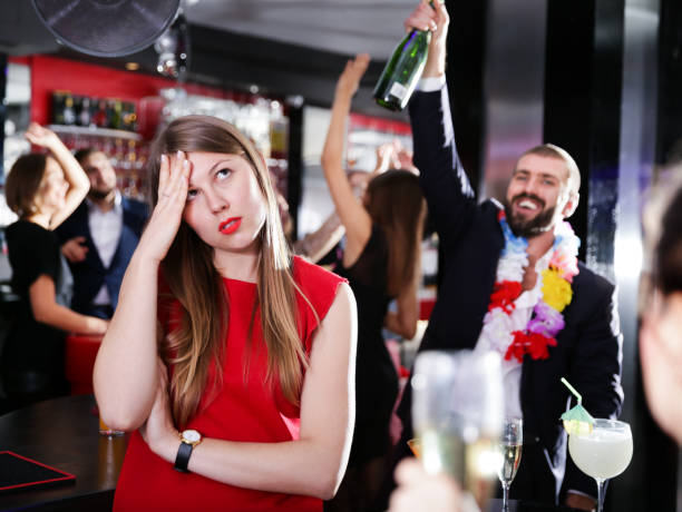 Offended woman on background with drunk man Offended young woman on background with drunk man on party at a nightclub vex nightclub stock pictures, royalty-free photos & images