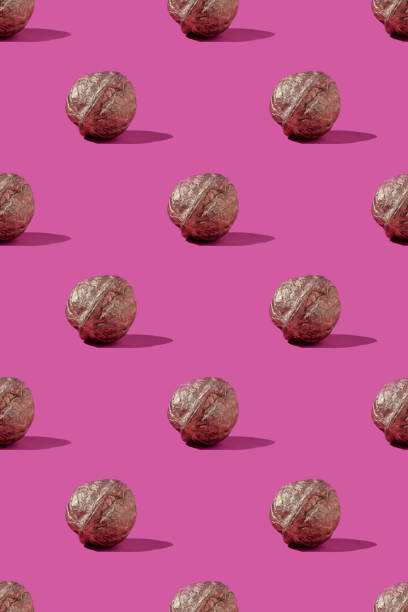 istock Pattern of golden walnuts on pink background 1294568690
