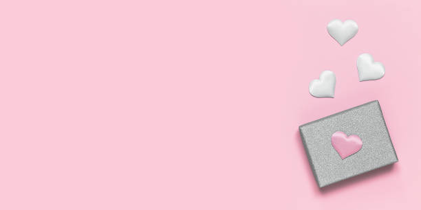istock Silver gift box with decorative hearts on a pink background. Gift for Valentine's Day. Banner 1294570473