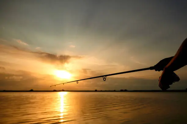 Man fishing at the lake in beautiful nature at lake during sunrise