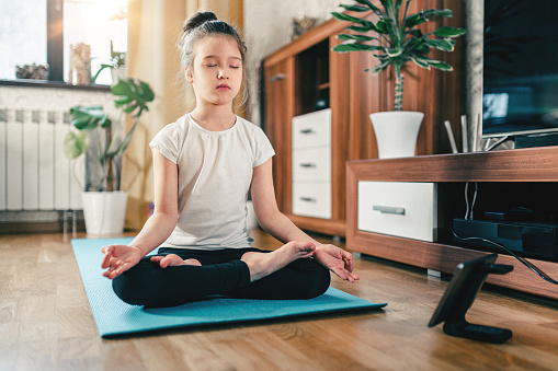 Entrenamiento de yoga en línea. Chica linda en casa con tableta digital en posición de loto photo