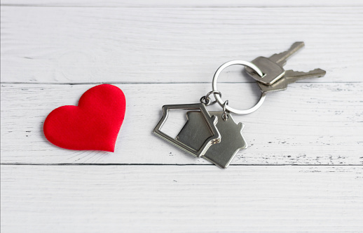 Keys and keychain in the form of a house with a heart. The concept of real estate as a gift