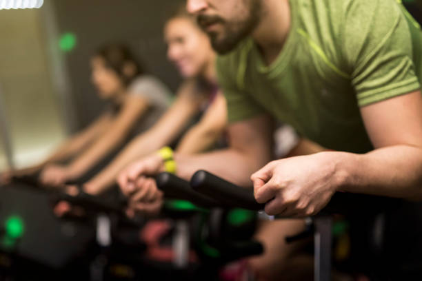 zamknięty wizerunek grupy osób trenujących w klasie spin z rowerami - spinning gym cycle cycling zdjęcia i obrazy z banku zdjęć