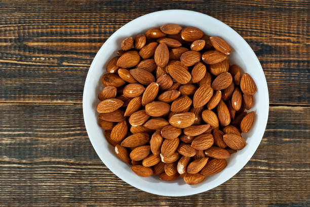 istock Almonds in a white bowl on an old shabby board. Nuts on a brown wooden table. 1294581885