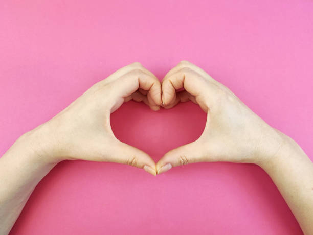 istock Female hands make heart shape on pink background 1294582286