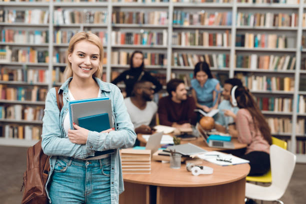 istock Group of ethnic multicultural students in library. White girl with notebooks. 1294582542