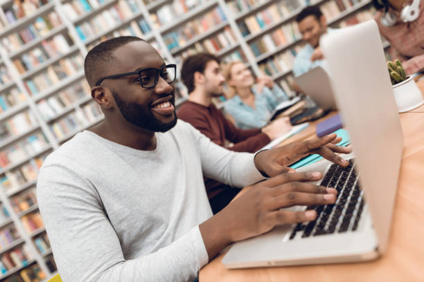 istock Group of ethnic multicultural students in library. Black guy on laptop. 1294582589