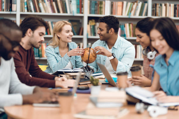 istock Group of ethnic multicultural students in library. Students are talking and reading. 1294582699