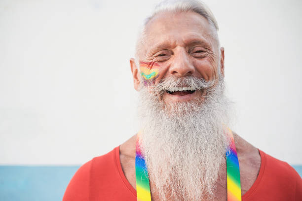 シニアヒップスターゲイの男性はカメラに微笑む - 顔に焦点を当てる - homosexual rainbow gay pride flag flag ストックフォトと画像