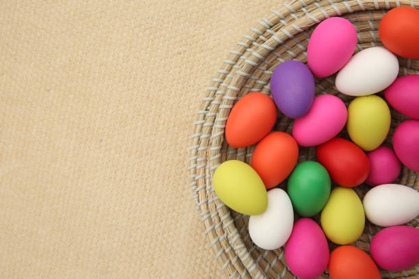istock Brightly colored easter eggs, in a straw basket against a beige background. 1294583418
