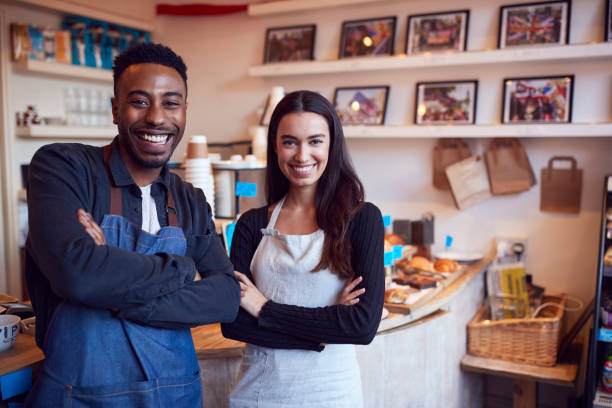 Portrait Of Smiling Couple Running Coffee Shop Together Standing Behind Counter Portrait Of Smiling Couple Running Coffee Shop Together Standing Behind Counter african american business couple stock pictures, royalty-free photos & images
