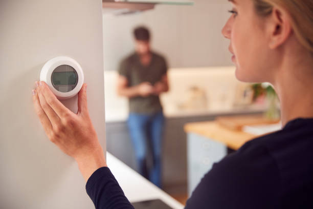 primer plano de la mujer ajustando la pared montada en la pared digital central calefacción termostato control en el hogar - termostato fotografías e imágenes de stock