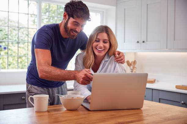 istock Couple Wearing Pyjamas In Kitchen Watching Laptop Whilst Eating Breakfast 1294587449