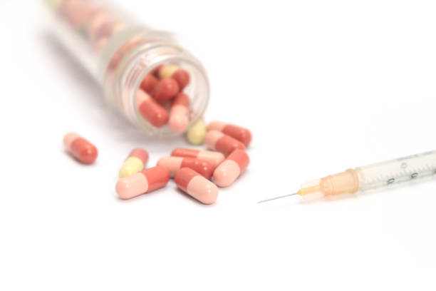 istock Medicine capsule and a syringe on white background 1294589264