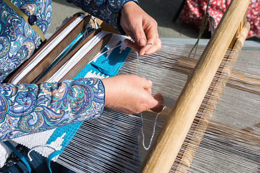 Folk Art Festival. A woman makes fabric on a hand loom. The fabric is made by hand.