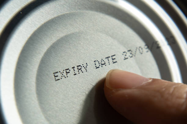 finger pointing at the expiry date on canned food - obsolete imagens e fotografias de stock