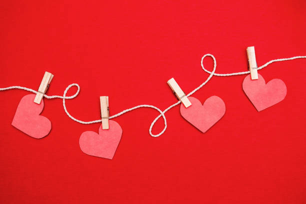 istock Paper hearts hanging on red background.Valentine's day concept. Flat lay, top view, copy space. 1294595154