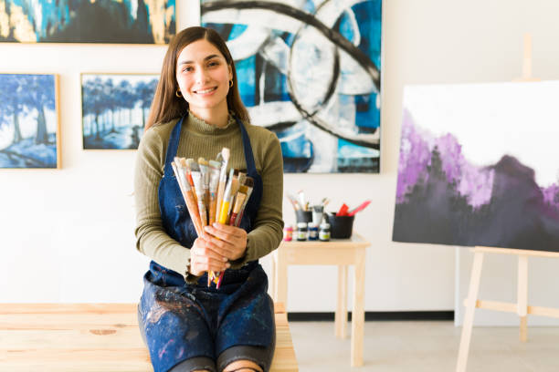 Latin young woman holding her many paintbrushes