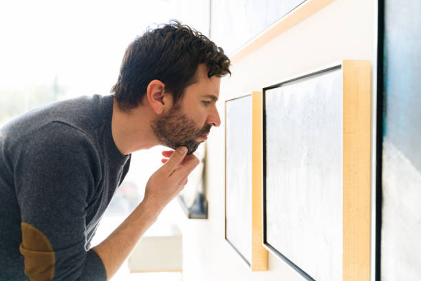 istock Hispanic man studying closely a painting at the gallery 1294597118