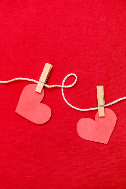 istock Paper hearts hanging on red background.Valentine's day concept. Flat lay, top view, copy space. 1294598873