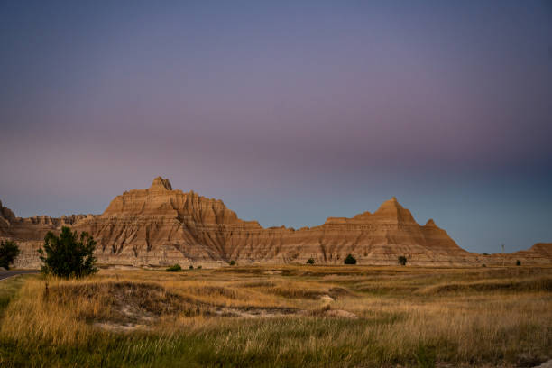 istock Late Afternoon Light Falls Across Badlands Formation and Field 1294601399