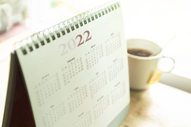 Paper desktop calendar 2022 Paper desktop calendar 2022 schedule with tea cup on wooden desk january stock pictures, royalty-free photos & images