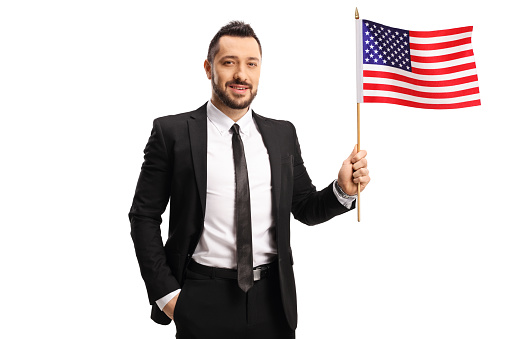 Smiling man in a suit and tie holding a USA flag isolated on white background